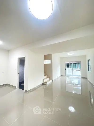 Spacious modern living room with glossy tiled floors and ample natural light