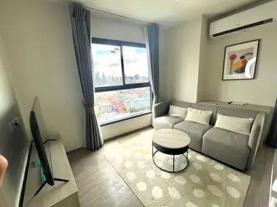 Modern living room with city view, stylish decor, and natural light.
