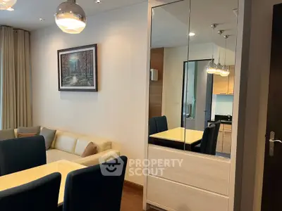 Modern living room with elegant decor and dining area, featuring stylish lighting and wall art.