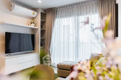 Modern living room with large TV and air conditioning, featuring elegant curtains and cozy seating.