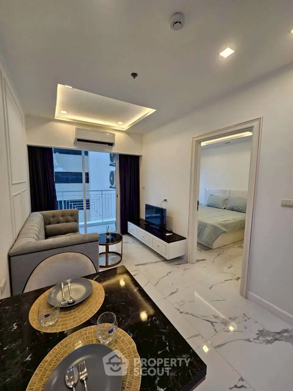 Modern open-plan living room with elegant decor and a glimpse of a cozy bedroom.
