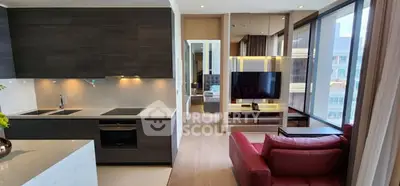 Modern open-plan living room with sleek kitchen and stylish red sofa in a contemporary apartment.