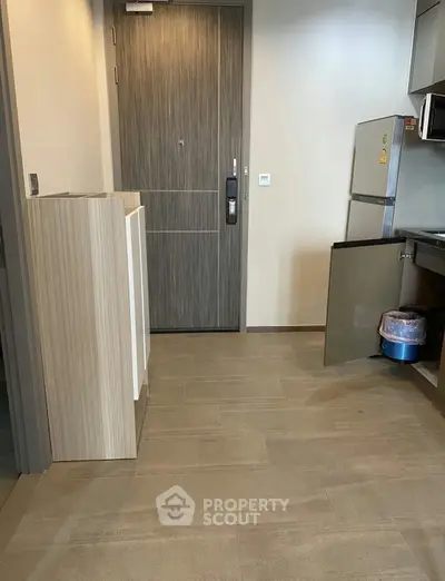 Modern kitchen entrance with sleek cabinetry and compact fridge in a stylish apartment.