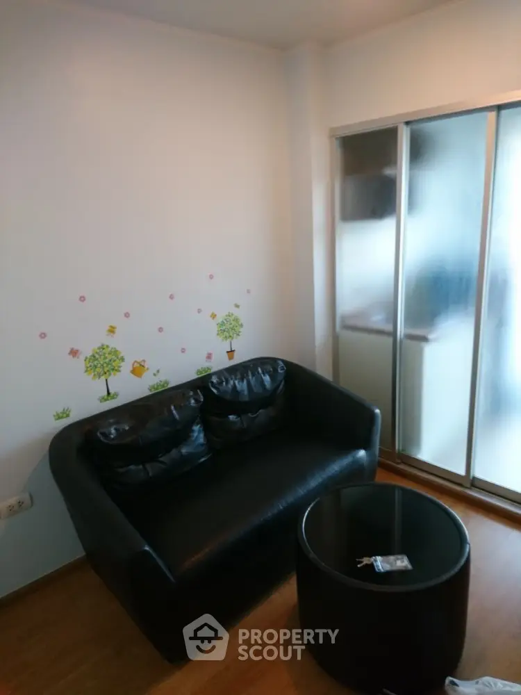 Cozy small living room with black sofa and round table, sliding glass door