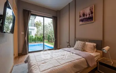 Cozy bedroom with pool view, modern decor, and natural light in a luxurious home.