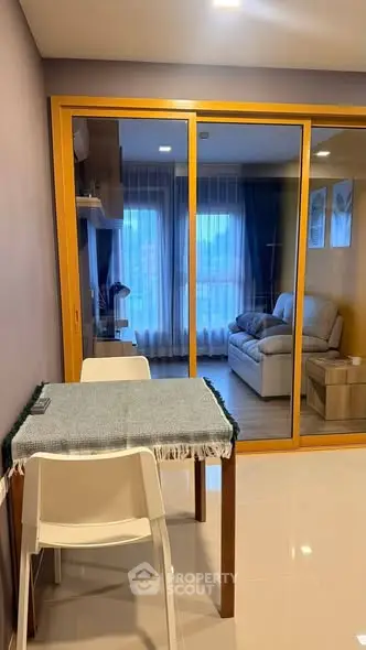 Modern apartment interior with cozy living room and dining area, featuring glass partition and stylish decor.