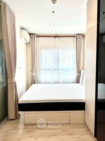 Bright and cozy bedroom with large window and modern furnishings, perfect for relaxation.