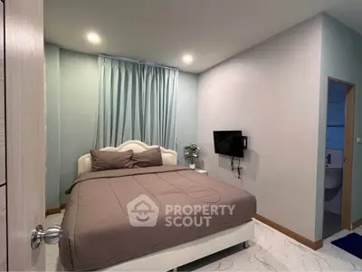 Cozy bedroom with modern decor and wall-mounted TV, perfect for relaxation.