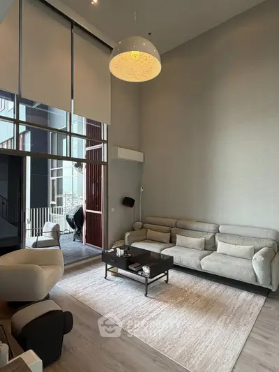 Luxurious modern living room with high ceilings and elegant furnishings, featuring a spacious balcony view.