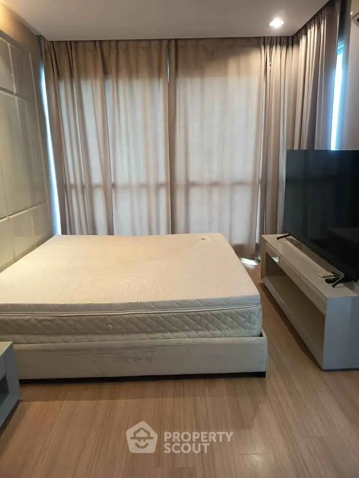 Modern bedroom with minimalist design, featuring a comfortable bed and large TV, perfect for relaxation.