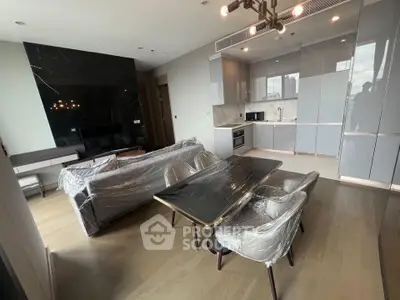 Modern open-layout living room with kitchen, featuring sleek furniture and contemporary design.