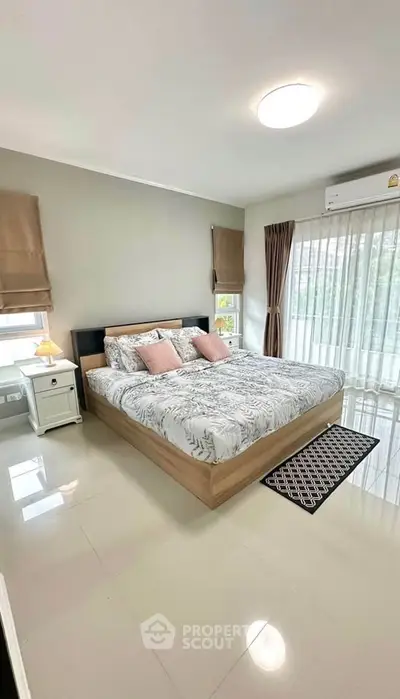 Modern bedroom with large bed and natural light, featuring elegant decor and cozy ambiance.