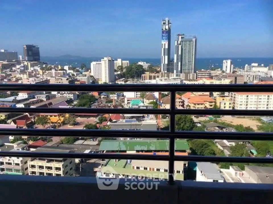 Stunning cityscape view from high-rise balcony overlooking urban skyline and ocean horizon.