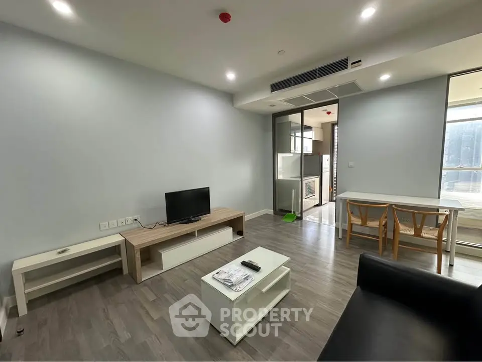 Modern living room with sleek furniture and open layout, featuring a TV and dining area.