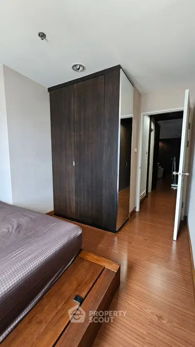 Modern bedroom with sleek wooden flooring and built-in wardrobe