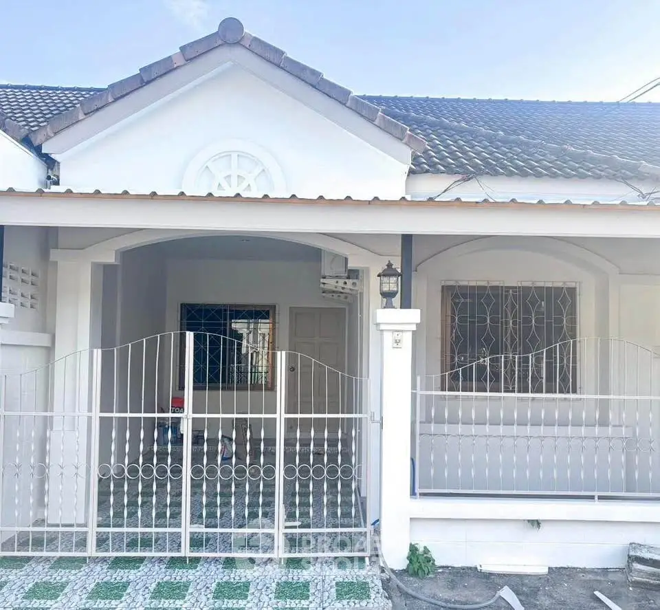 Charming single-story house with gated entrance and tiled roof, perfect for cozy living.