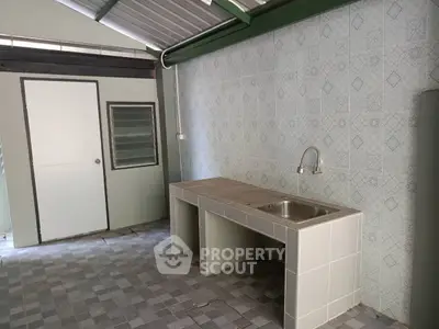 Spacious tiled kitchen area with modern sink and ample counter space.