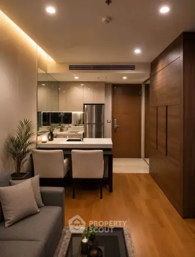 Modern living room with elegant decor and open kitchen layout, featuring stylish furniture and warm lighting.