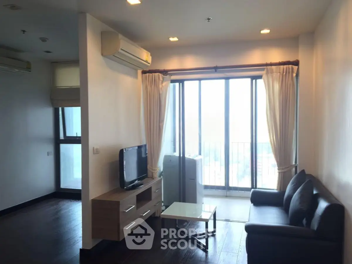 Modern living room with large windows and sleek furniture in a high-rise apartment.