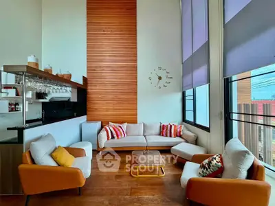 Modern living room with high ceilings, stylish furniture, and large windows for natural light.