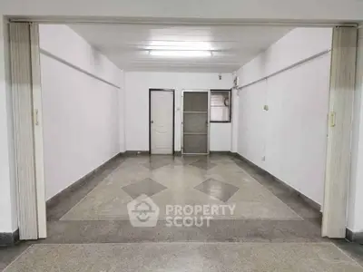 Spacious empty room with tiled floor and sliding doors, ideal for customization.