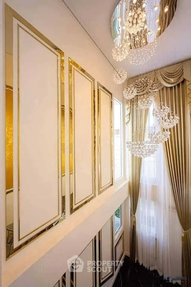 Luxurious high-ceiling living room with elegant chandeliers and floor-to-ceiling windows.