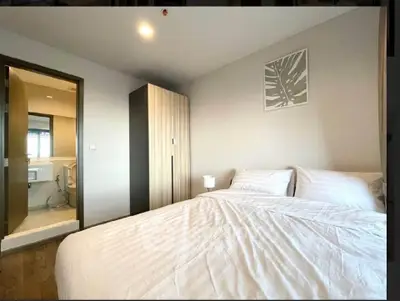 Modern bedroom with ensuite bathroom, featuring a cozy bed and sleek wardrobe in a stylish apartment.