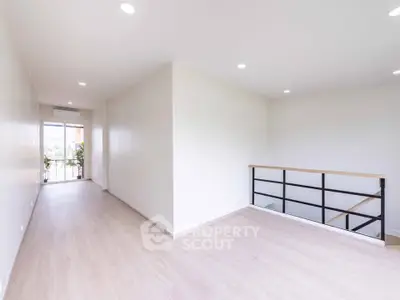 Spacious modern interior with wooden flooring and natural light, featuring a balcony view.