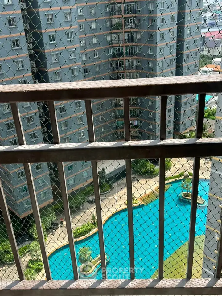Stunning view from balcony overlooking pool and modern high-rise building.