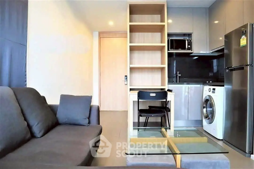 Modern apartment living room with sleek kitchen and washing machine, perfect for urban living.
