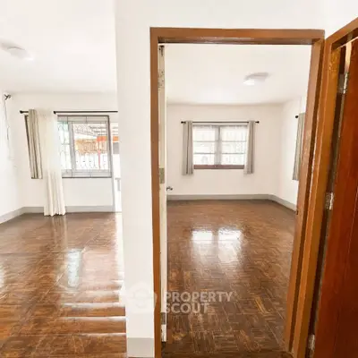 Spacious and bright interior with polished wooden floors and large windows in a modern home.