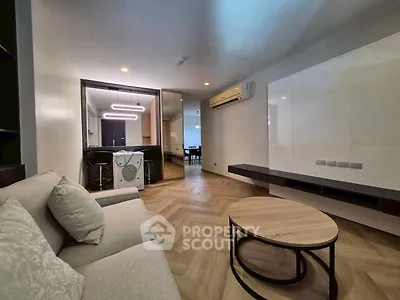 Modern living room with stylish furniture and open layout, featuring a washing machine and sleek lighting.