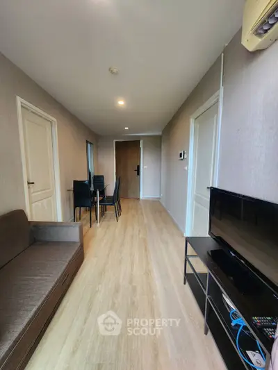 Modern living room with wooden flooring, sofa, and TV setup in a cozy apartment.
