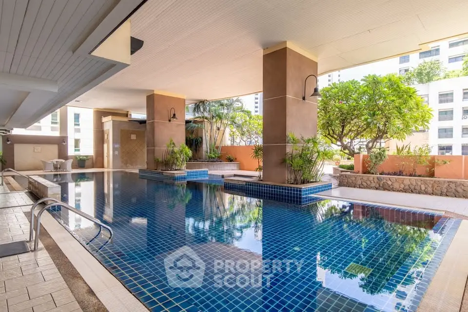 Luxurious condominium pool area with modern design and lush greenery, perfect for relaxation and leisure.
