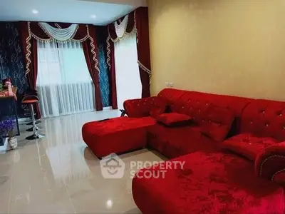Luxurious living room with plush red sofa and elegant drapery, perfect for stylish entertaining.