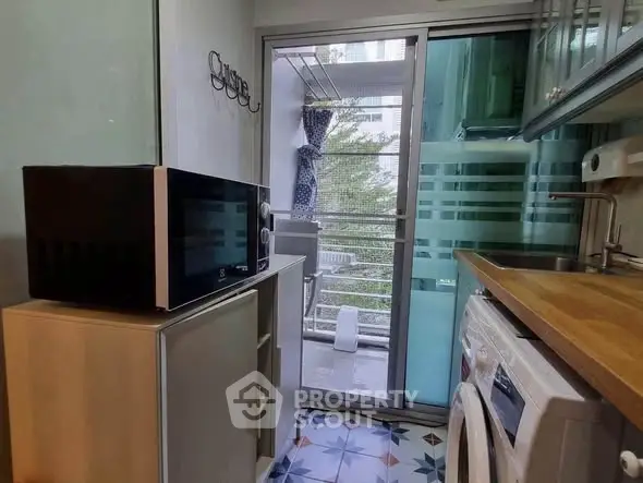 Compact kitchen with modern appliances and balcony view in urban apartment