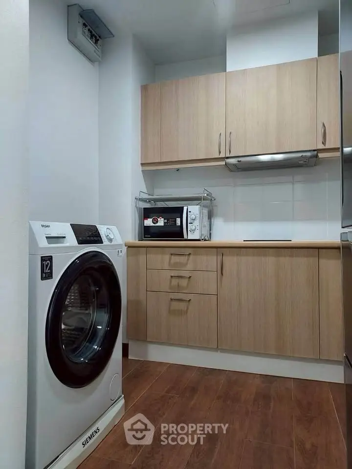 Modern kitchen with wooden cabinets and washing machine, featuring sleek appliances and efficient layout.