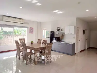 Spacious dining area with modern kitchen in open layout, featuring natural light and elegant furniture.