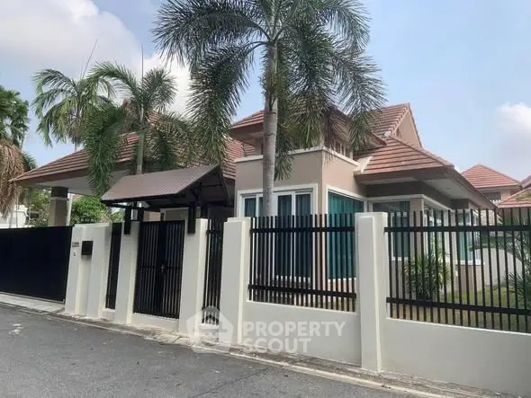 Charming suburban home with palm trees and gated entrance, perfect for family living.