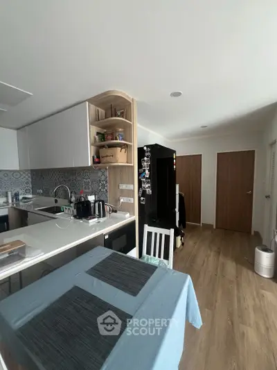 Modern kitchen with sleek design, featuring a black fridge, white cabinets, and a cozy dining area.
