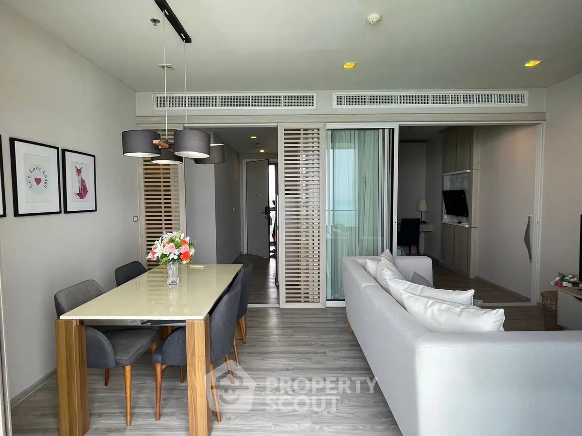Modern living room with dining area, stylish decor, and ocean view.