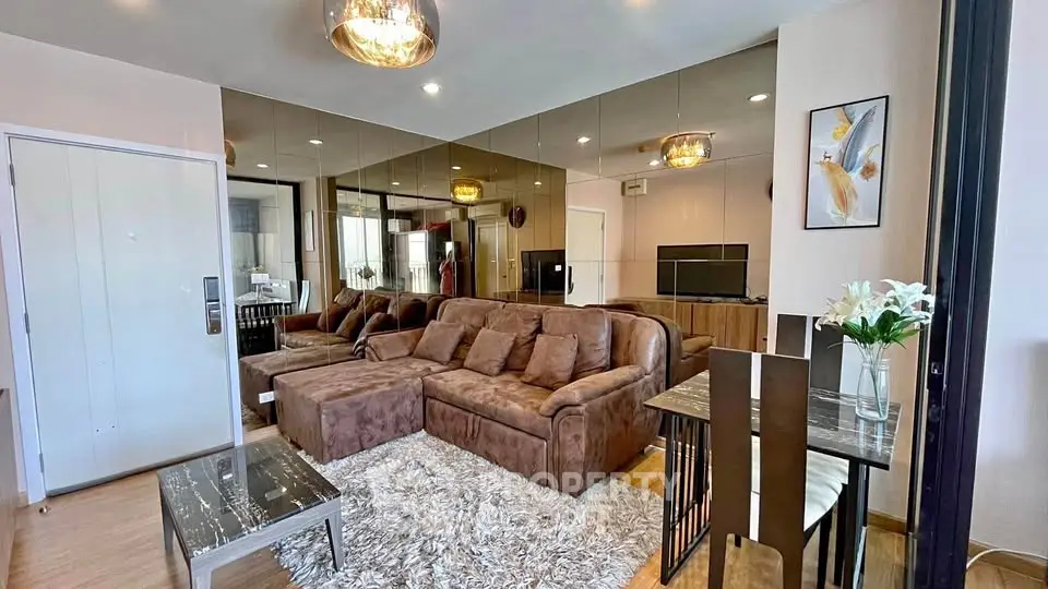 Luxurious living room with plush brown sofa, mirrored wall, and elegant lighting in modern apartment.