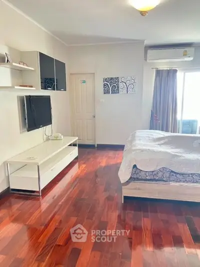 Spacious bedroom with wooden flooring and modern decor