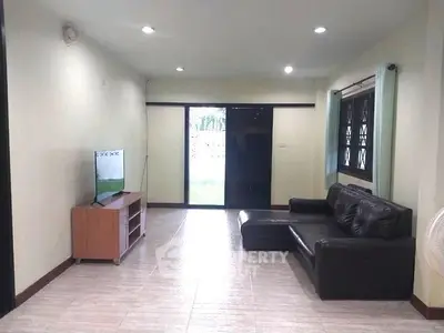 Spacious living room with modern sofa and TV, large windows for natural light.