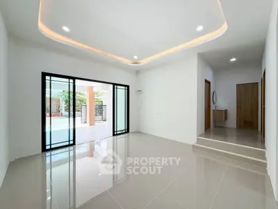 Spacious modern living room with sleek tile flooring and recessed lighting, featuring large sliding glass doors.