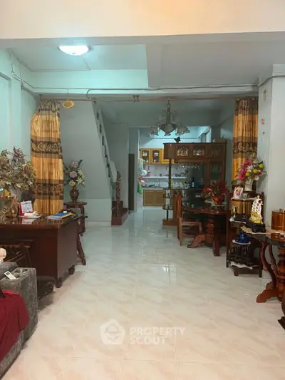 Spacious living room with elegant decor and open view to the kitchen, featuring classic wooden furniture.