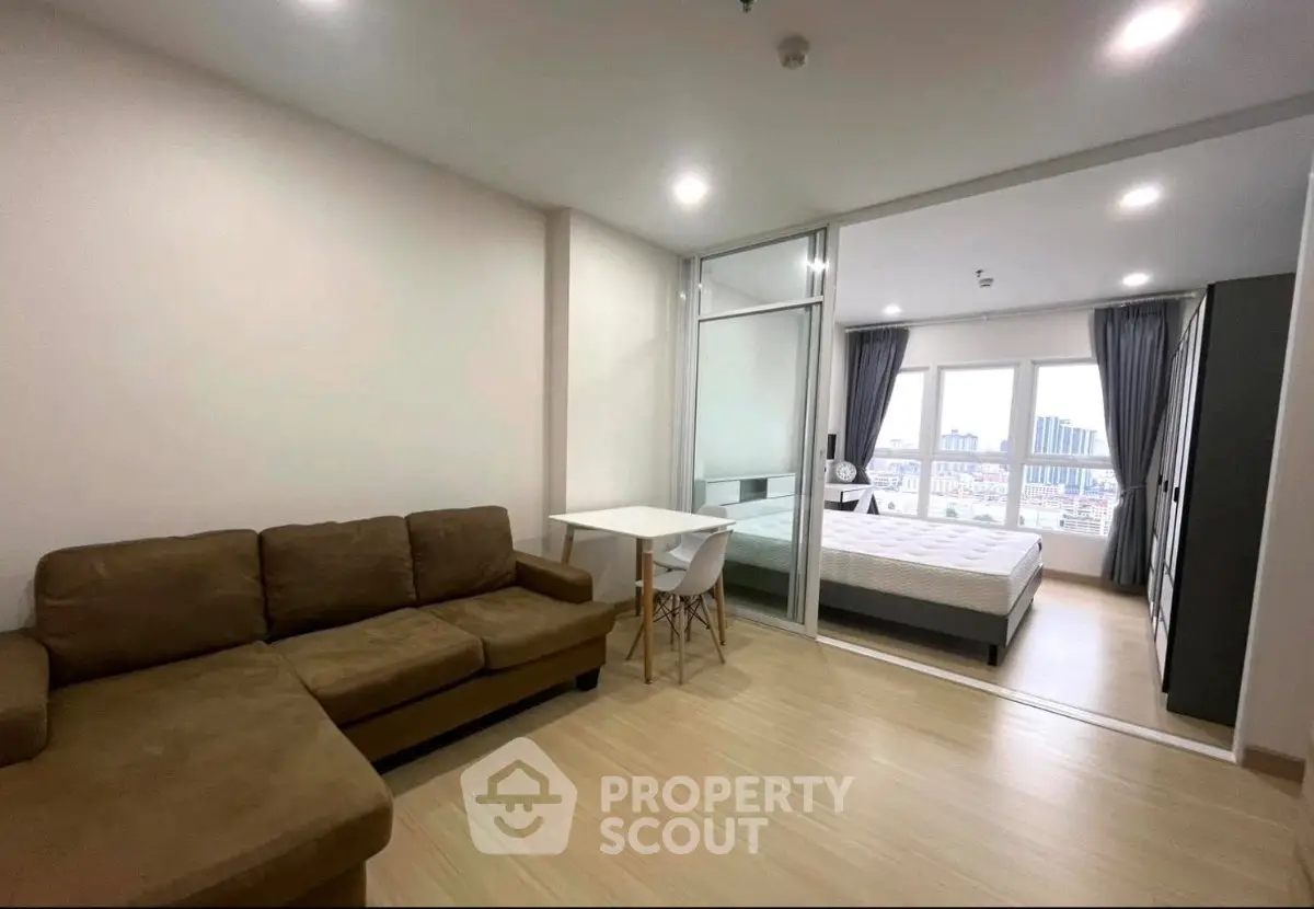 Modern studio apartment with cozy living area and bedroom, featuring large windows and city view.
