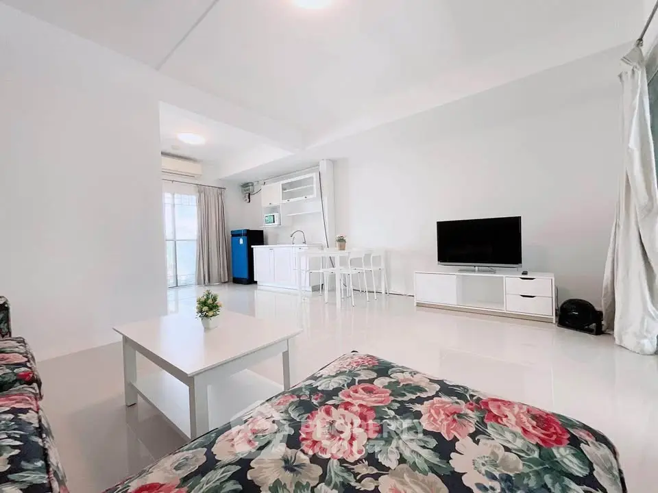 Spacious modern living room with open kitchen and floral sofa, ideal for family gatherings.