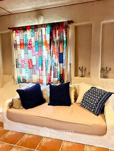 Charming living room with colorful patchwork curtains and cozy sofa, perfect for relaxation.