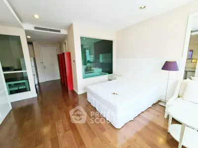 Spacious bedroom with wooden flooring and modern decor in a bright apartment.